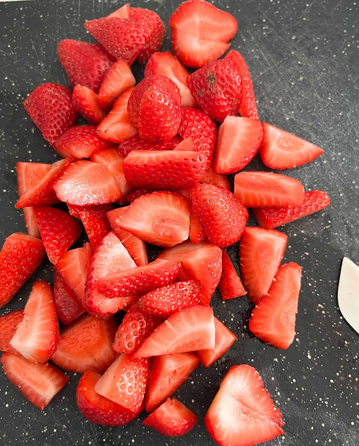Cut up strawberries on a plate. 