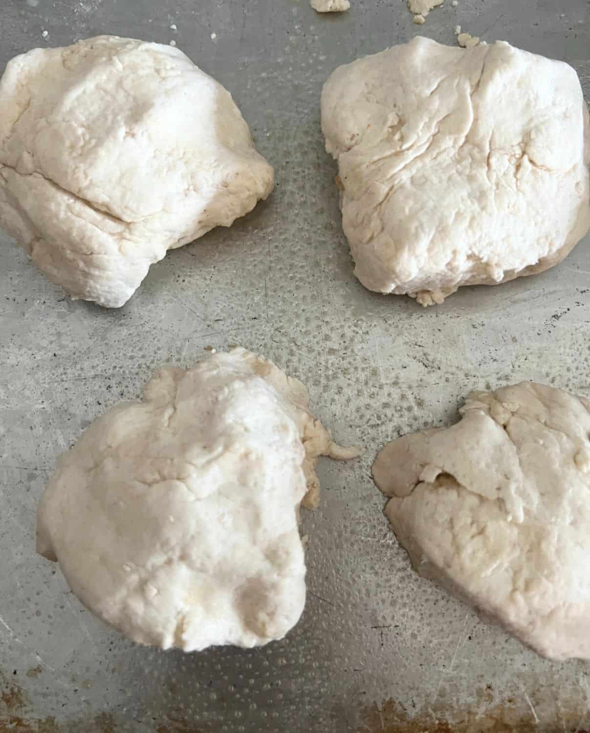 4 shaped biscuit dough balls on a baking pan. 