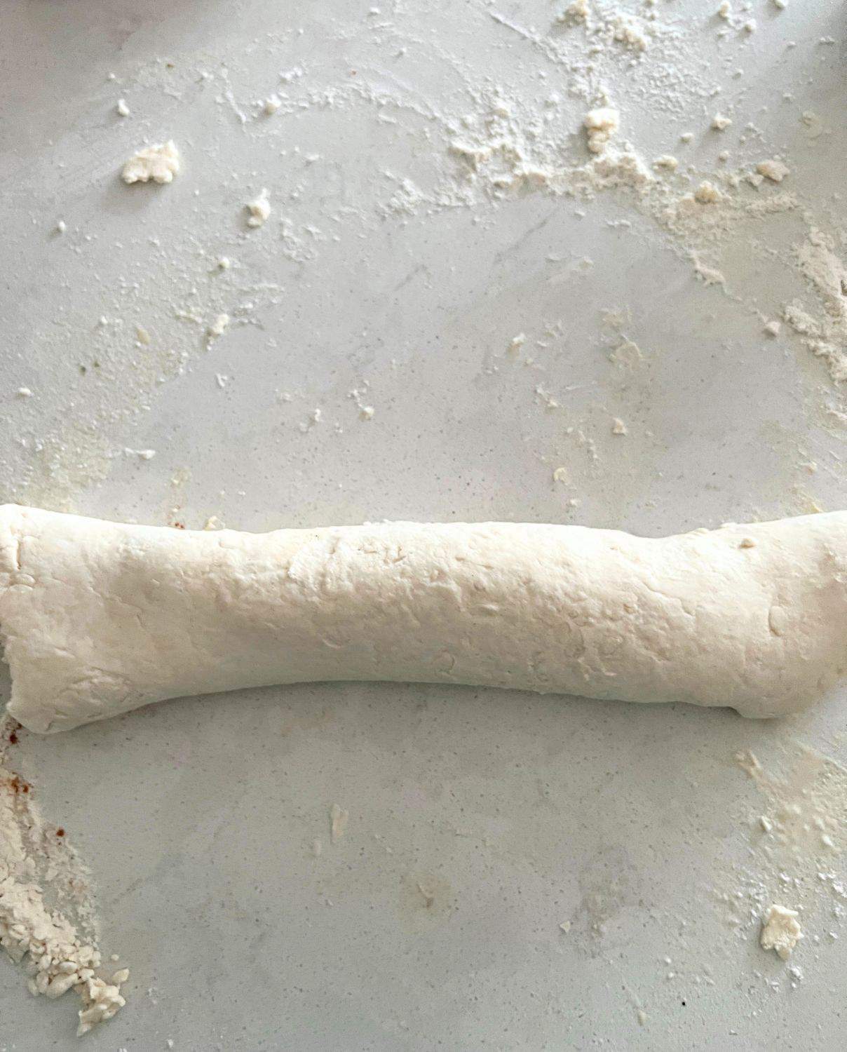 Cinnamon roll dough rolled up into a long retangular shape.