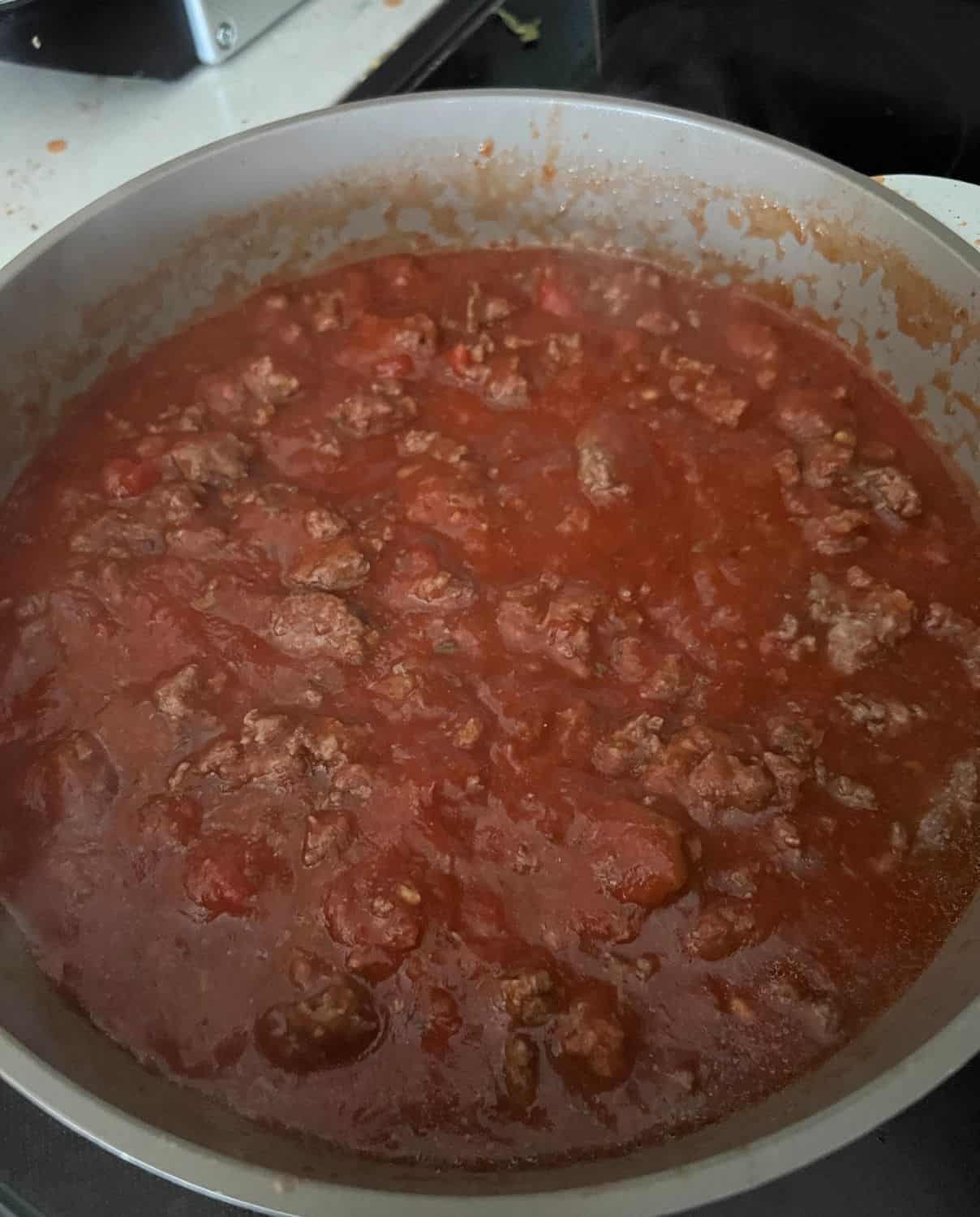 Ground beef and marinara cooking in a skillet. 