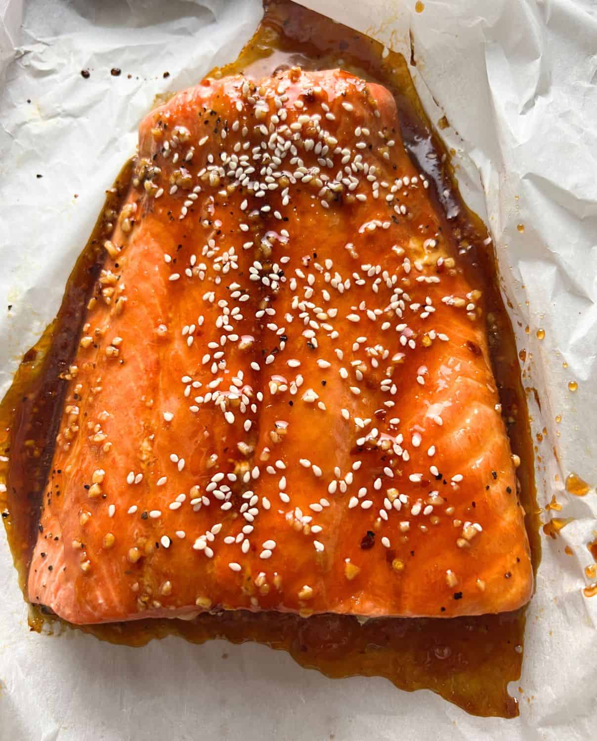 Firecracker salmon garnished with sesame seeds on parchment paper. 