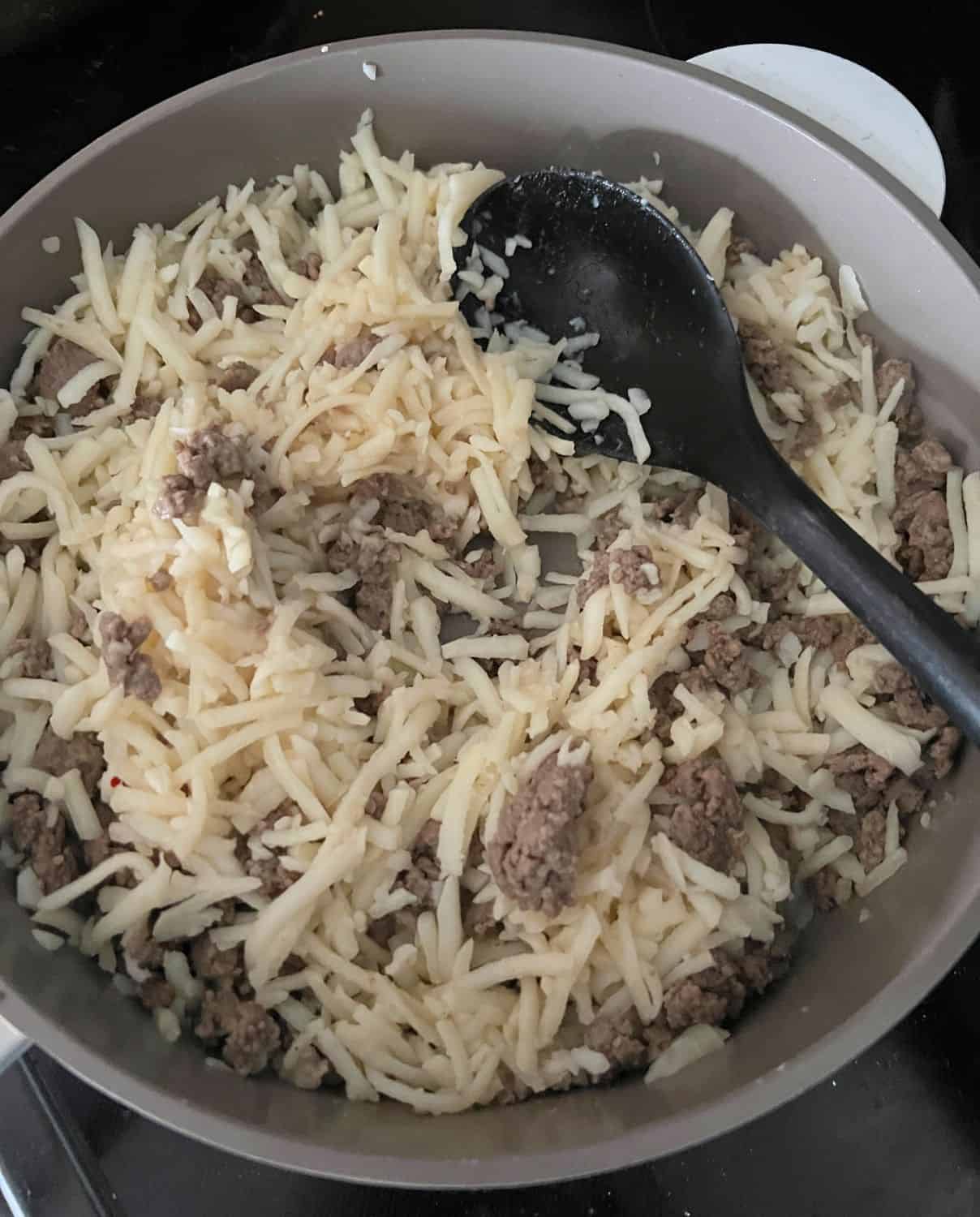 Hash browns and sausage cooked in a skillet. 