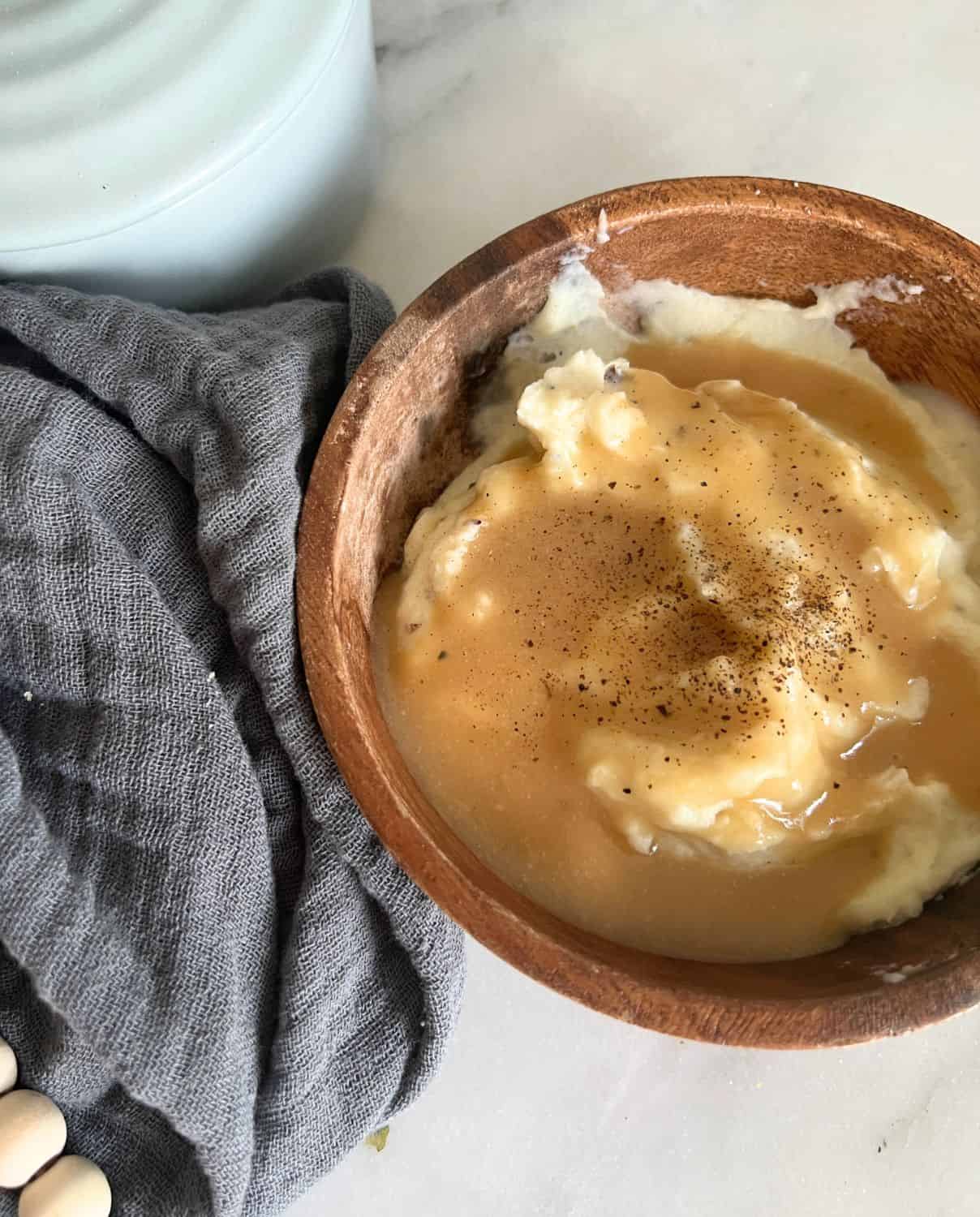 Homemade brown gravy on top of mashed potatoes in a brown bowl. 