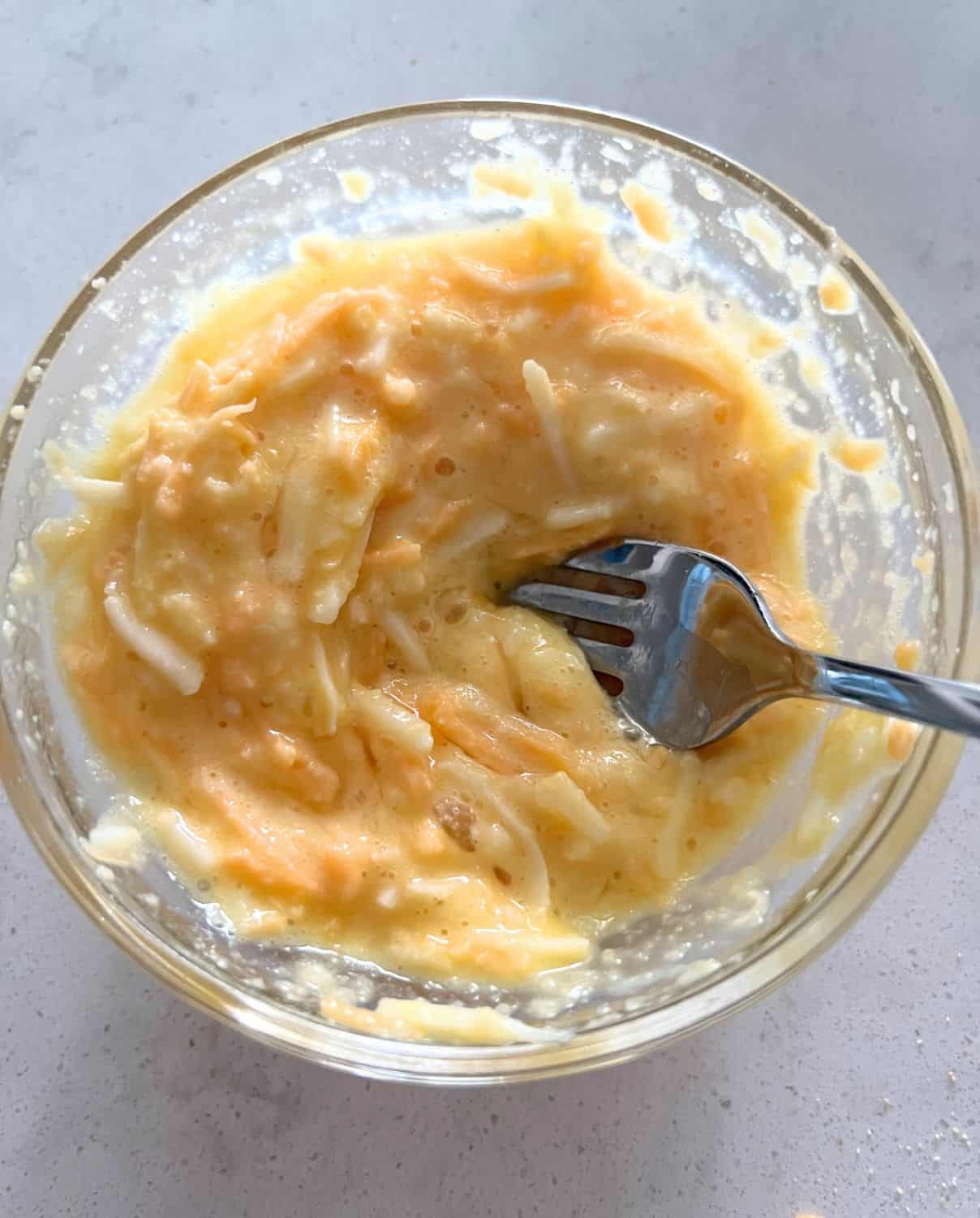 Egg, flour, and cheese mixed into a bowl. 