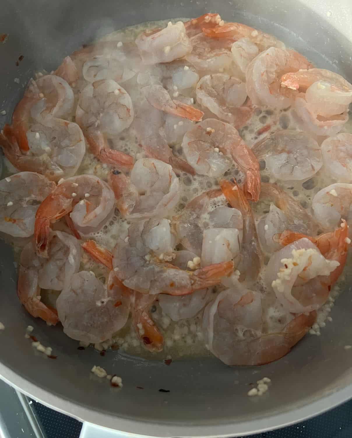 Shrimp with seasonings cooking in a skillet. 
