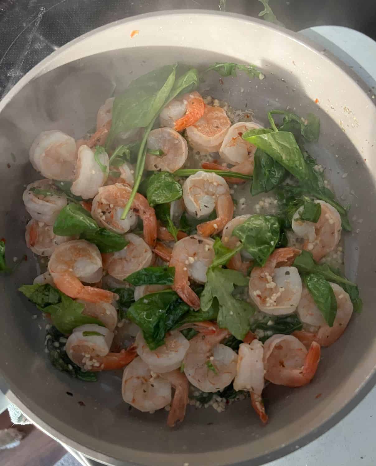 Spinach and shrimp cooked in a skillet. 