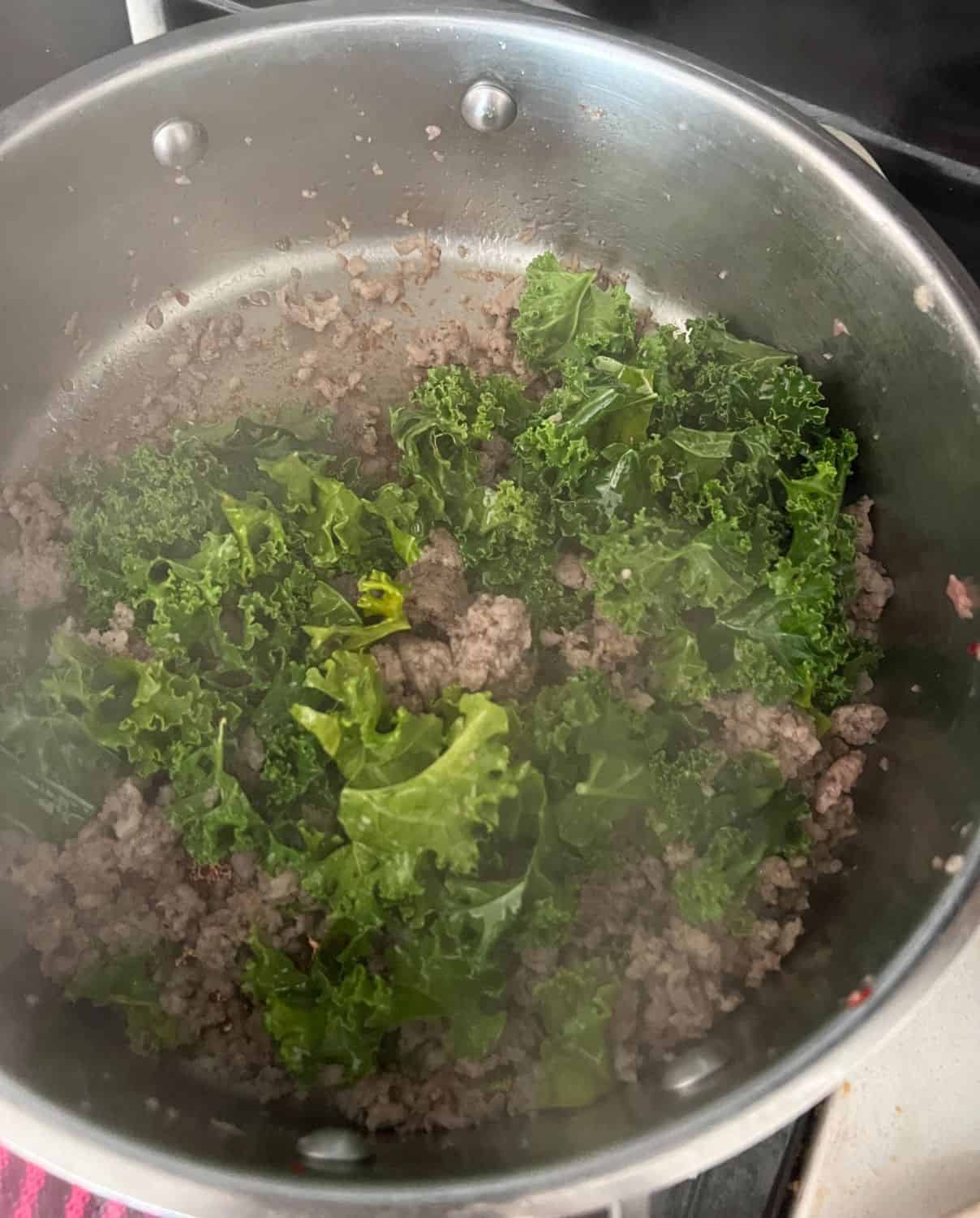 kale and sausage cooking in a skillet. 
