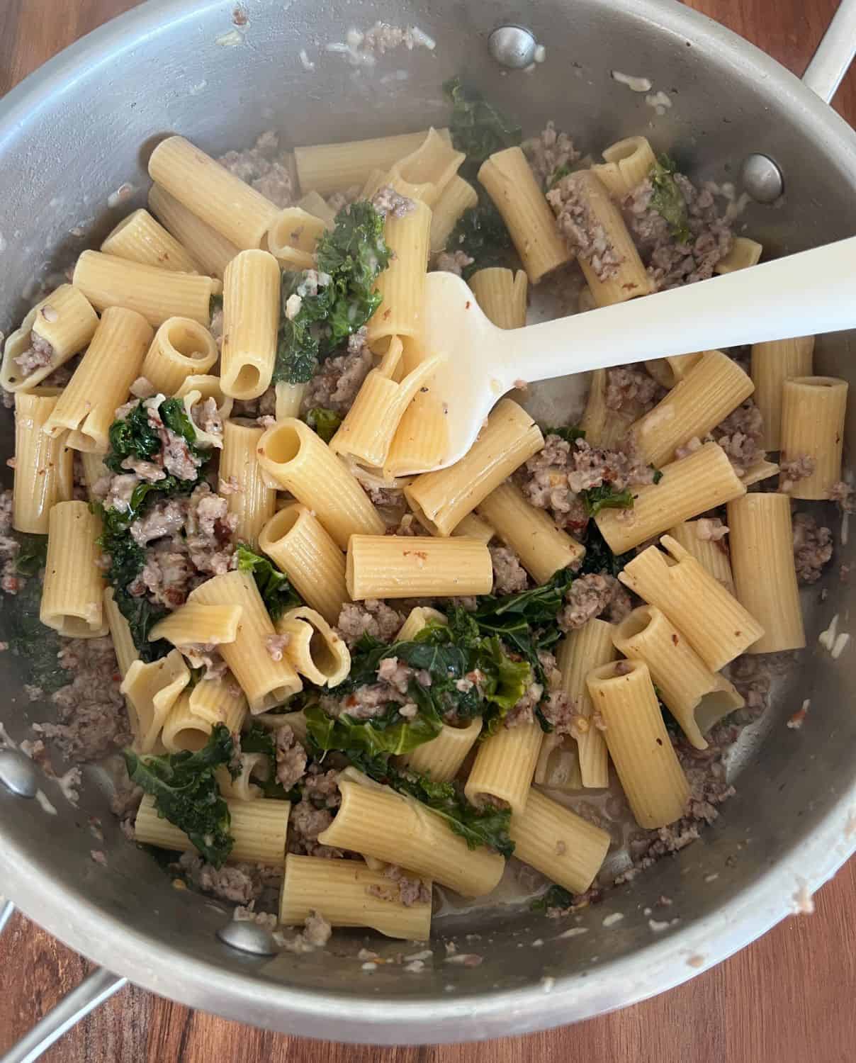 All the ingredients for kale and sausage rigatoni cooked in a pan. 