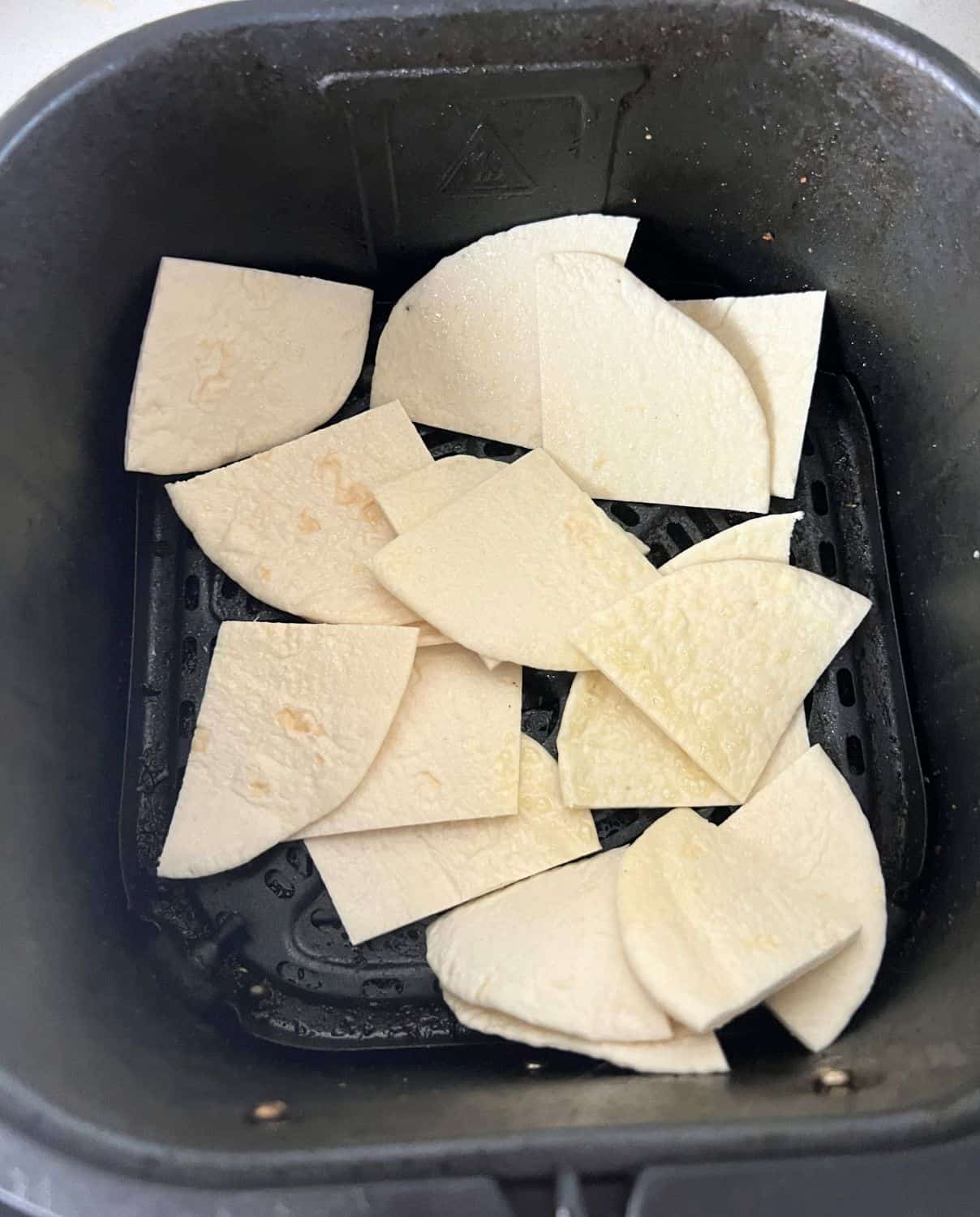 Tortilla Chips in an air fryer basket. 