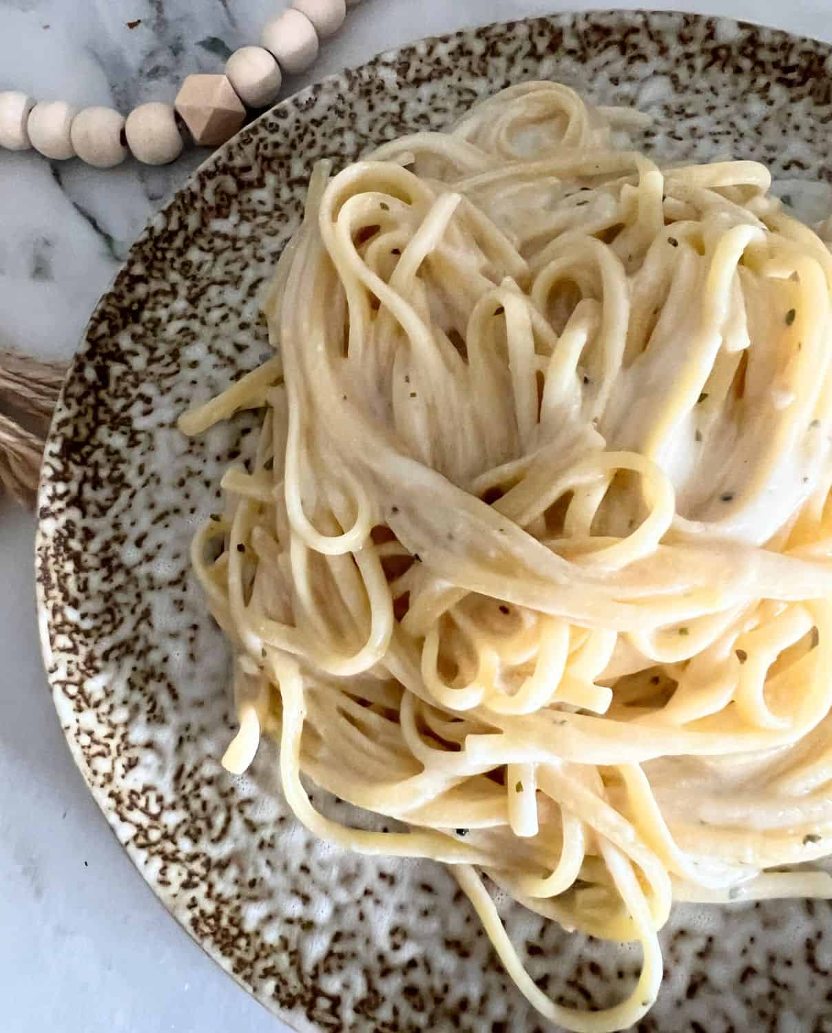 Finished alfredo sauce on a brown plate topped with parsley. 