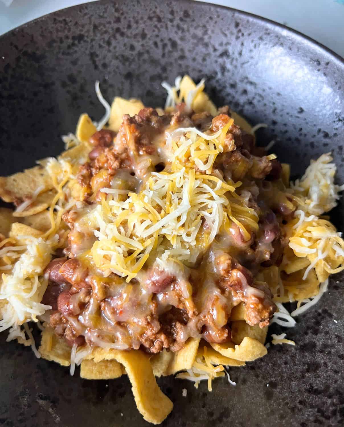 Chili on top of frito chips and cheese.