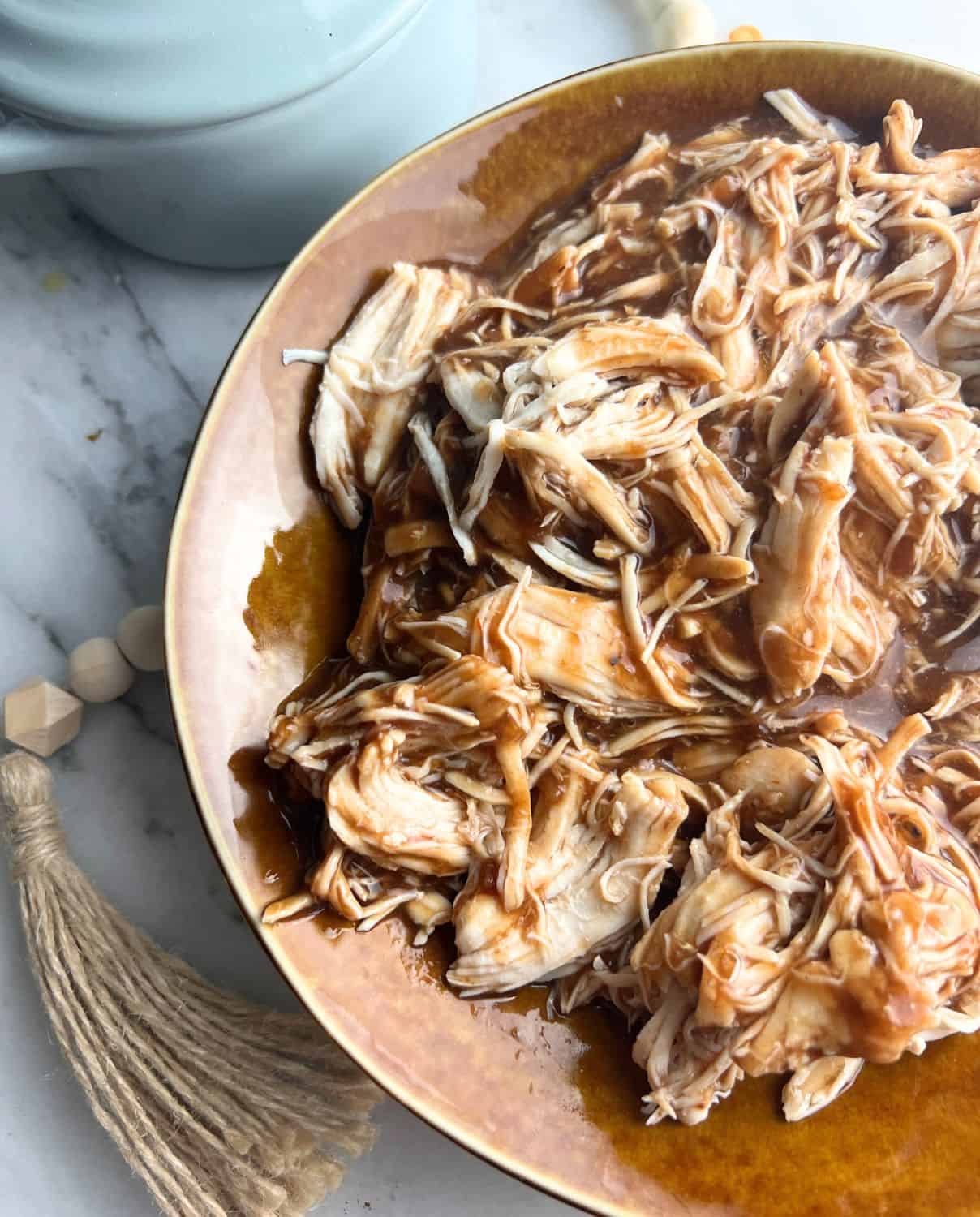 Shredded chicken with bbq sauce in a brown bowl. 