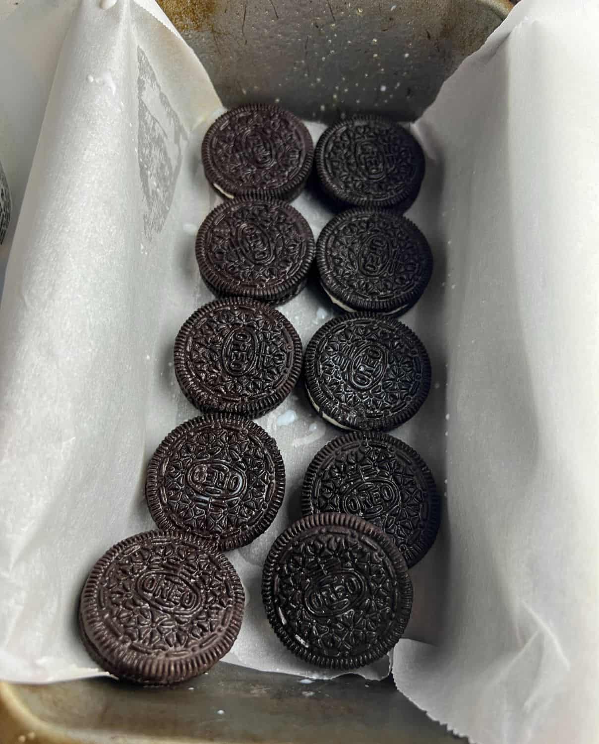 Oreos dipped in milk in a loaf pan. 