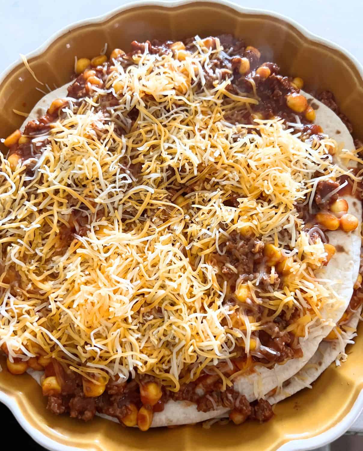 Beef and Corn mixture topped with tortillas in a casserole dish. Then cheese. 