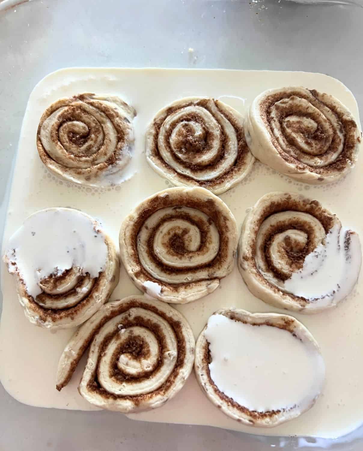 Cinnamon Rolls covered in heavy cream in a baking dish. 