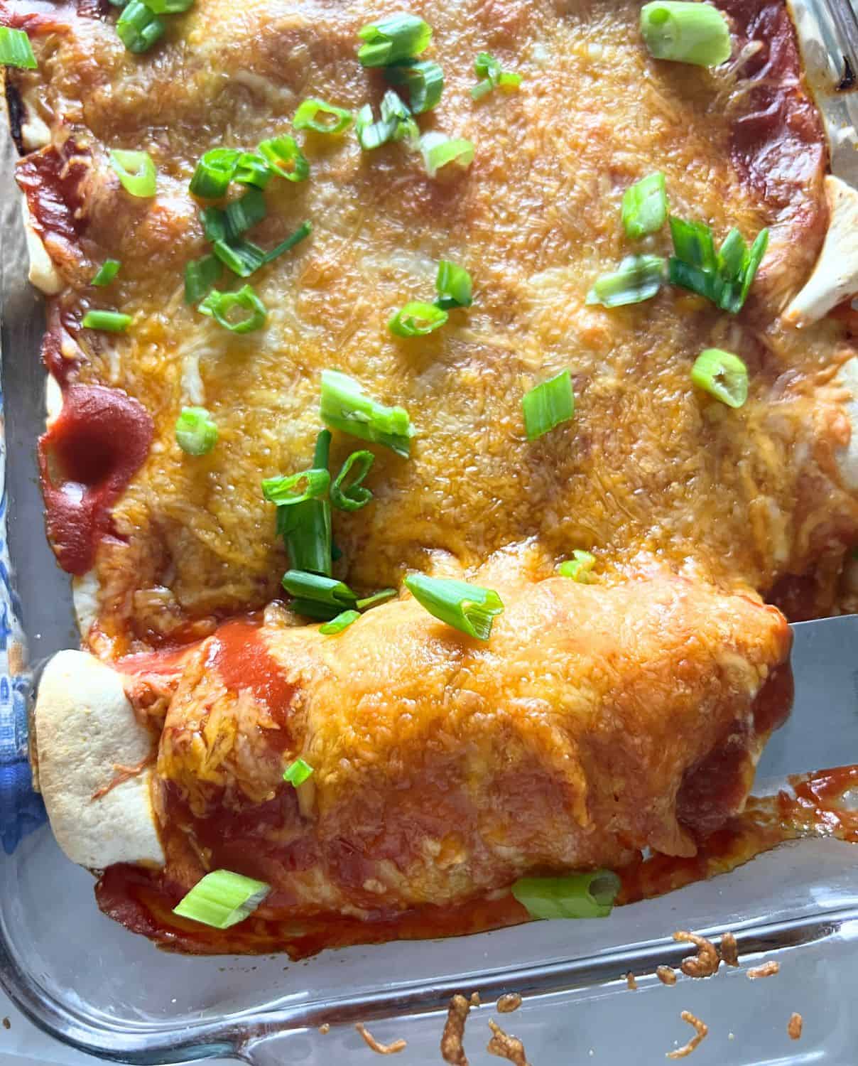 Healthy turkey enchiladas topped with melted cheese and enchilada sauce. 