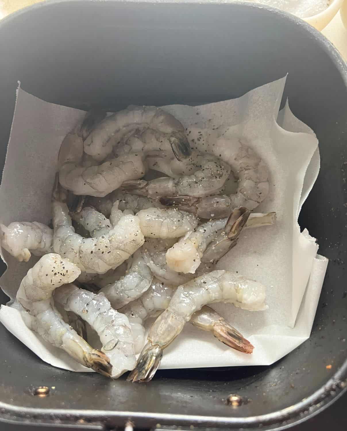 Shrimp in a single layer in an air fryer basket. 