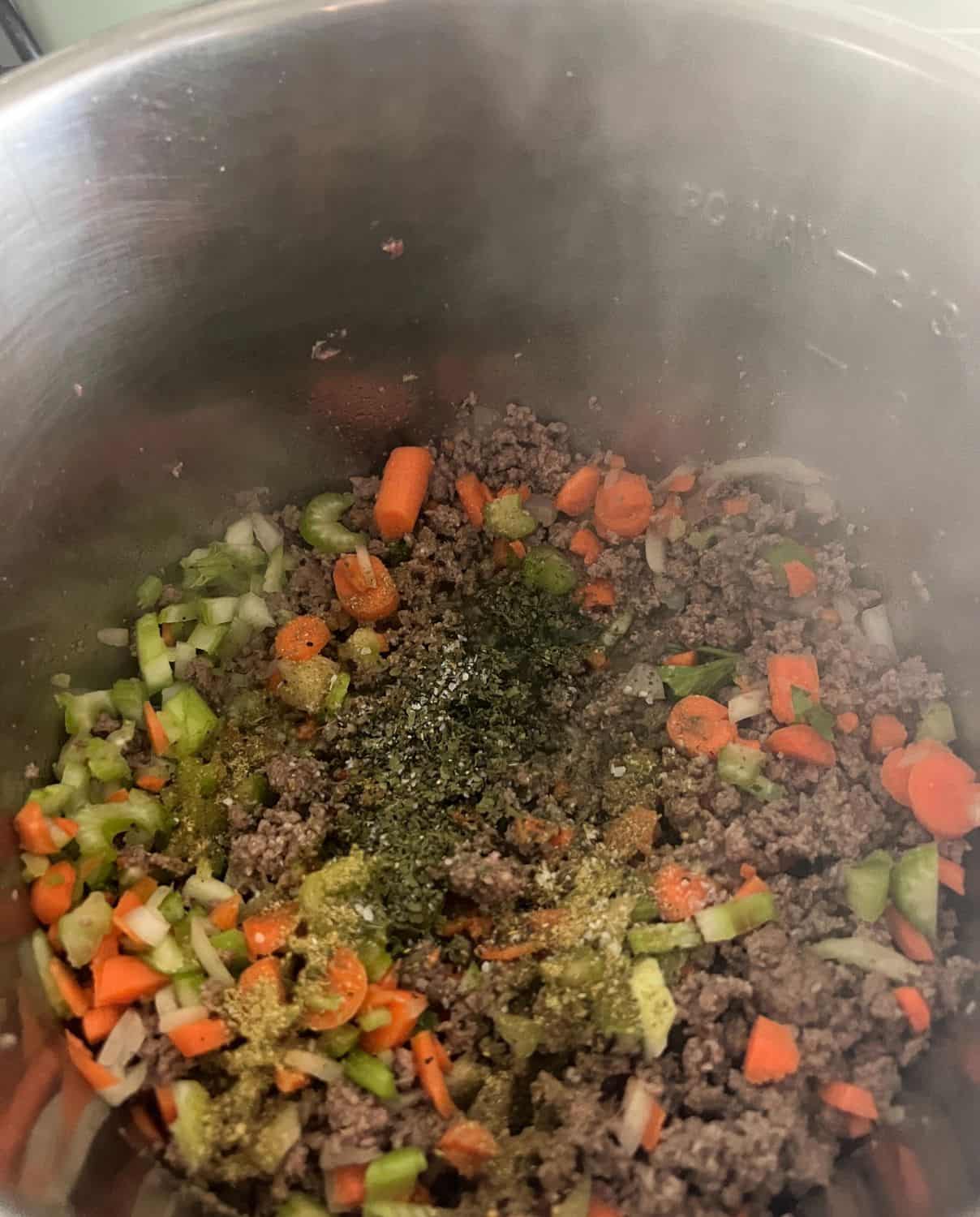 Ground beef stauteing in an Instant Pot with vegetables and seasonings. 