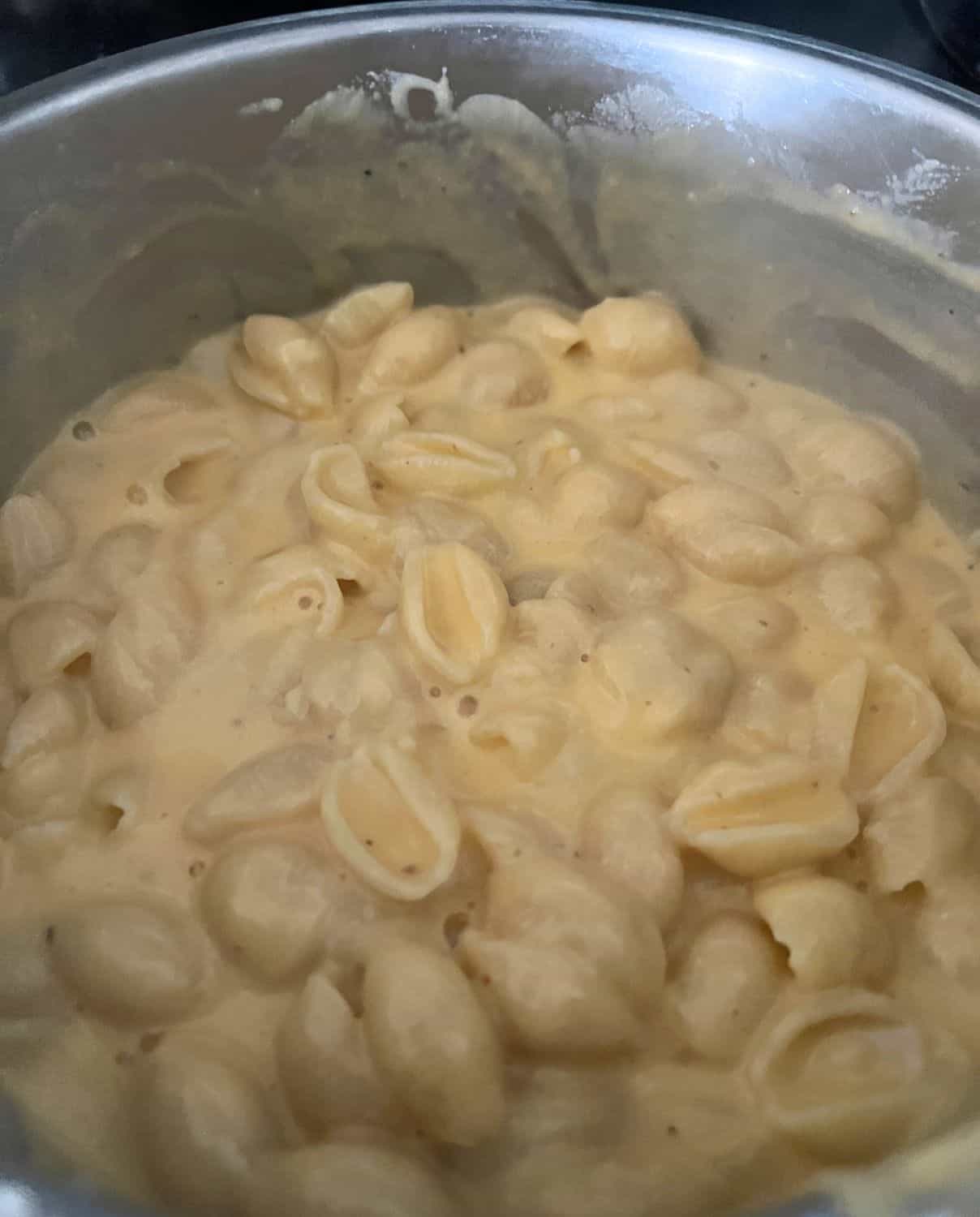 Melted cheese and noodles stirred together in a pot. 