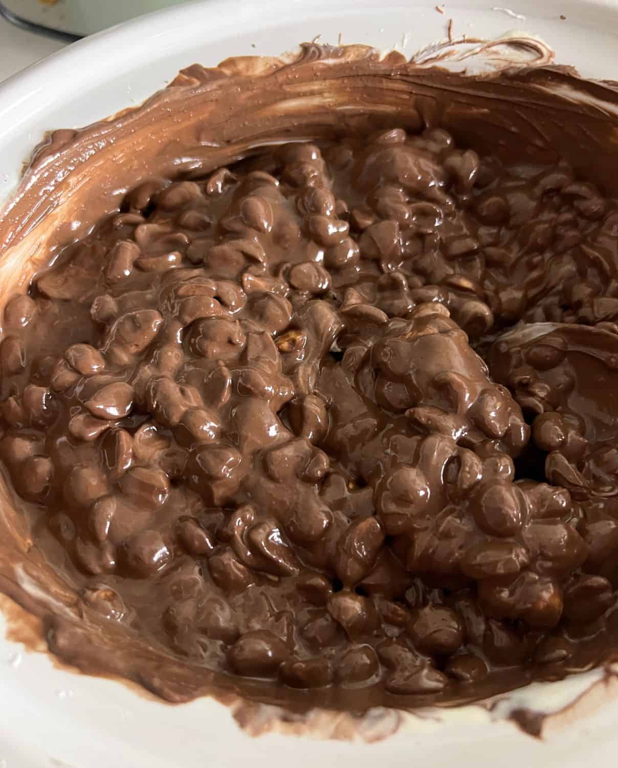 Melted chocolate and peanuts in a white slow cooker.