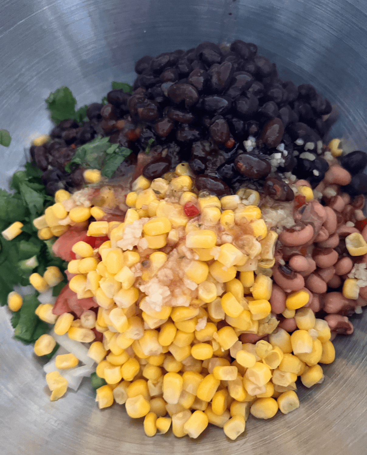 Cowboy caviar ingredients added together in a bowl. 
