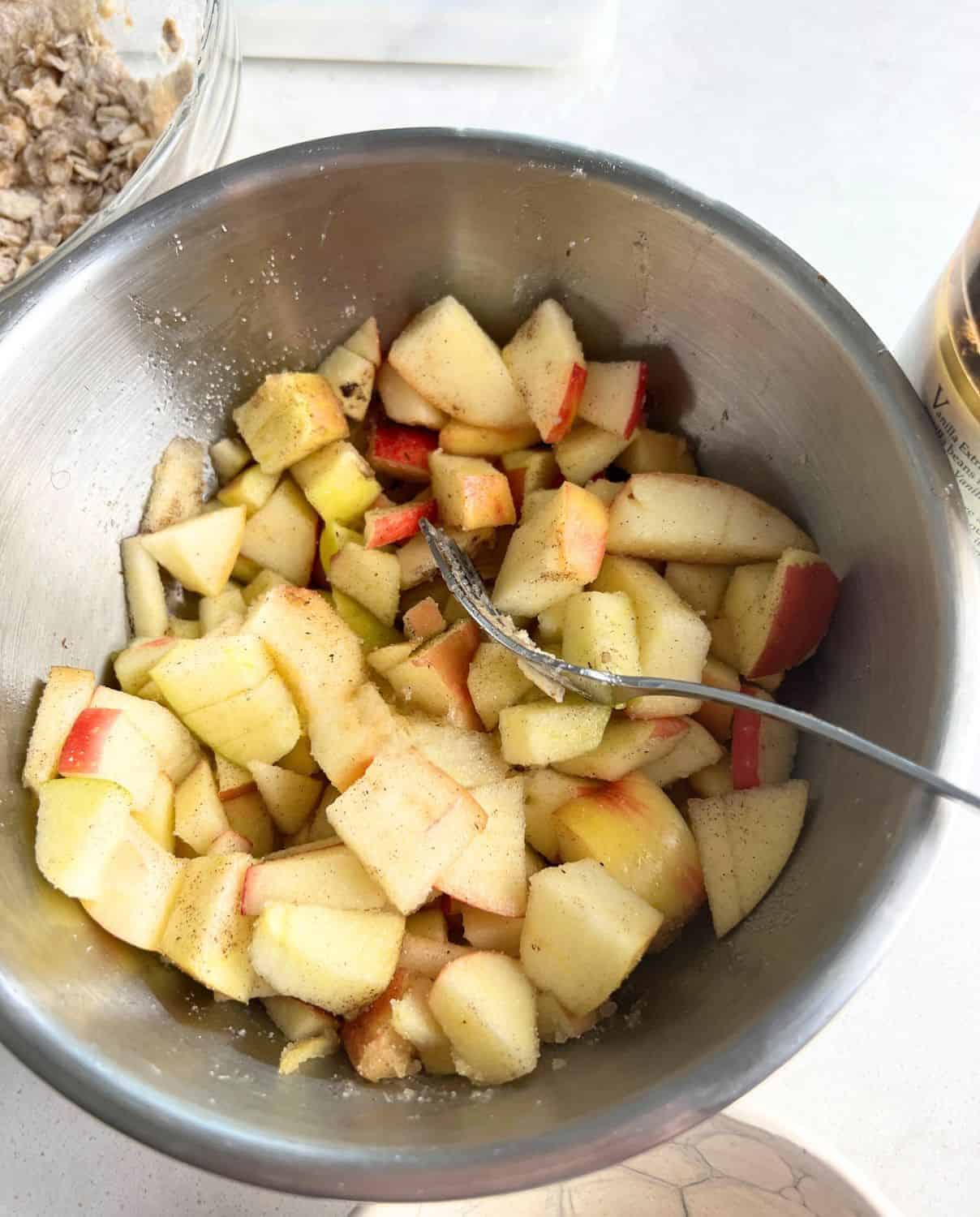 Apples in a bowl mixed with sugar and spices. 