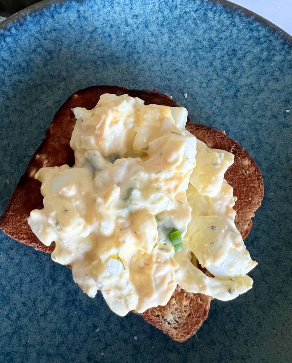 Egg salad on top of a toasted slice of bread. 