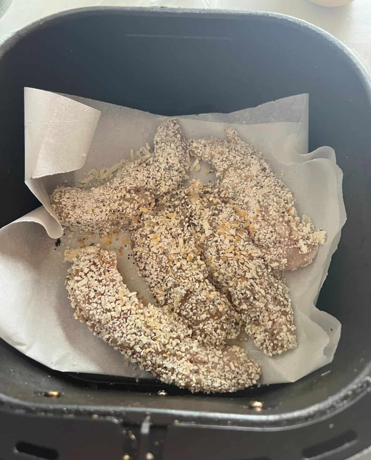 Chicken tenders in air fryer basket. 