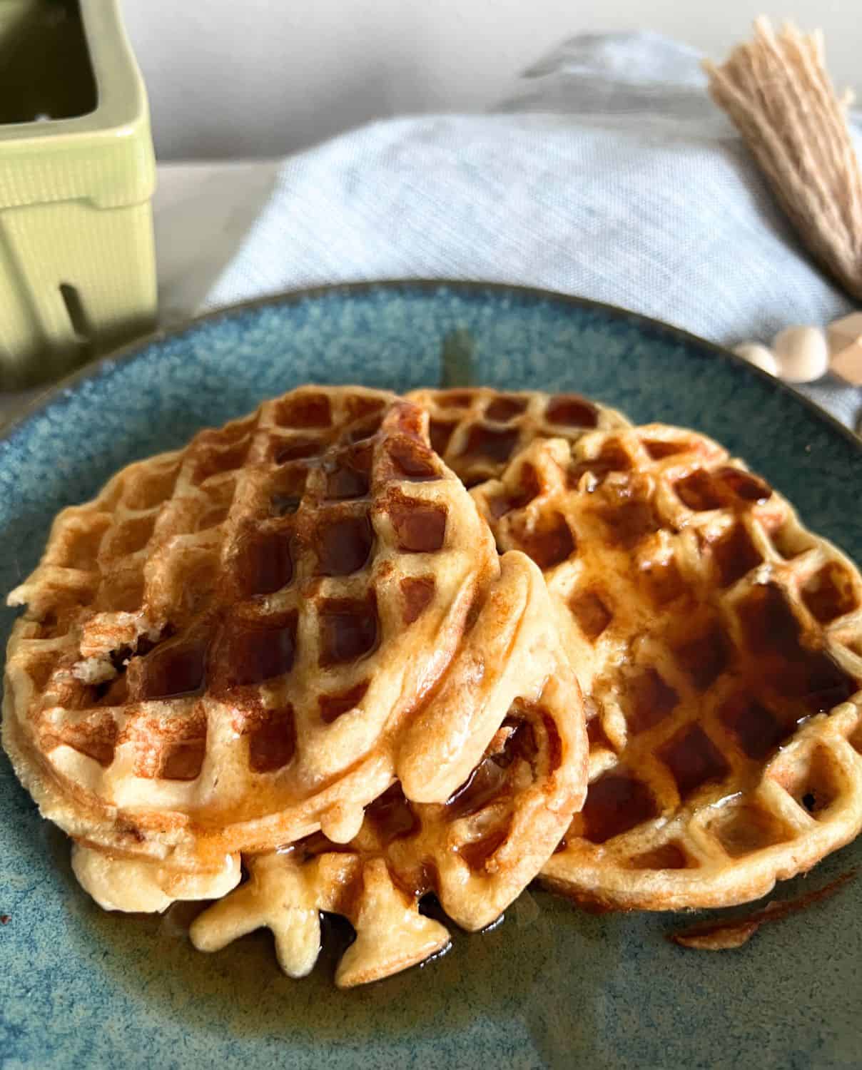 Protein waffles on a blue plate topped with maple syrup. 