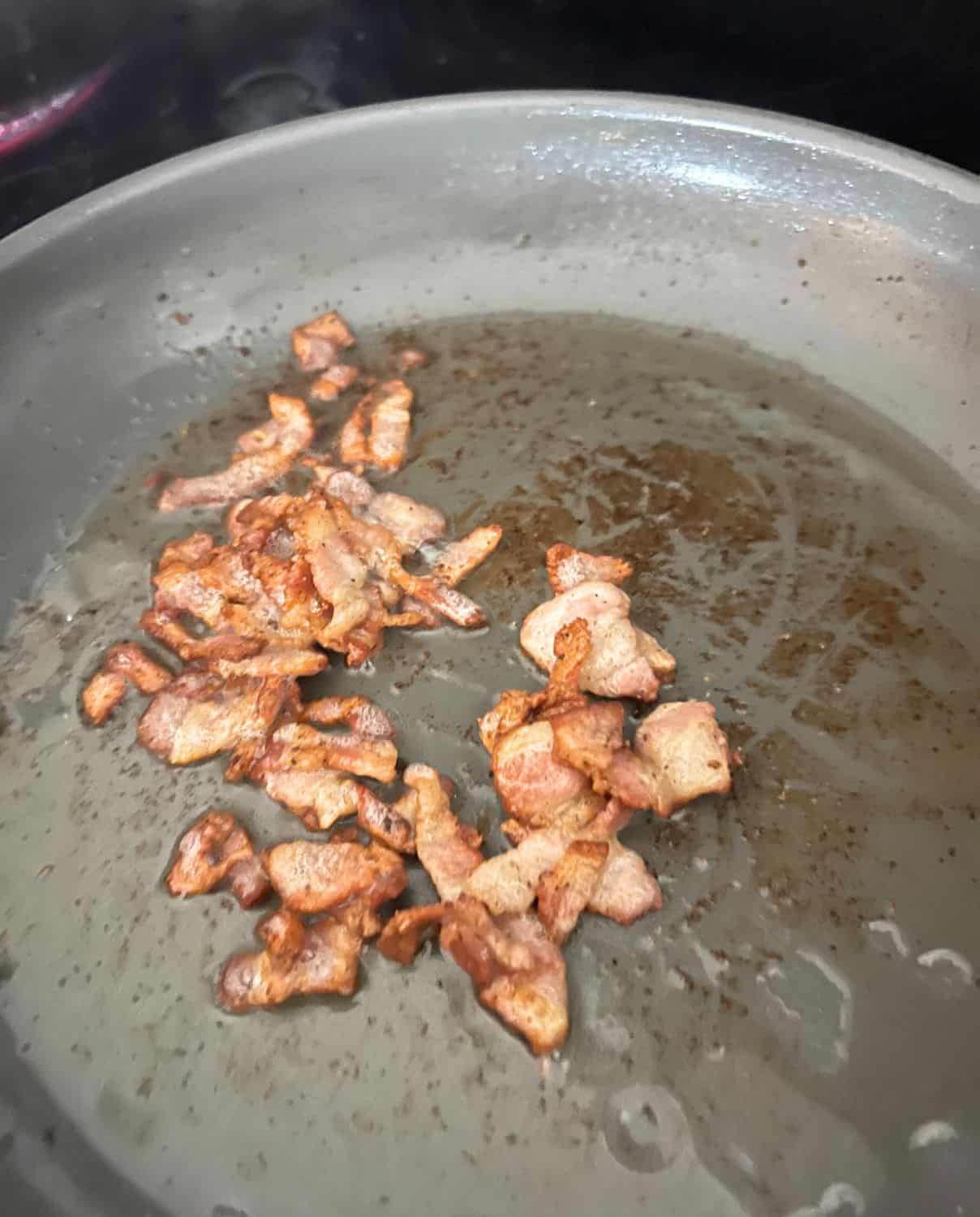 Crispy bacon cooking in a skillet. 