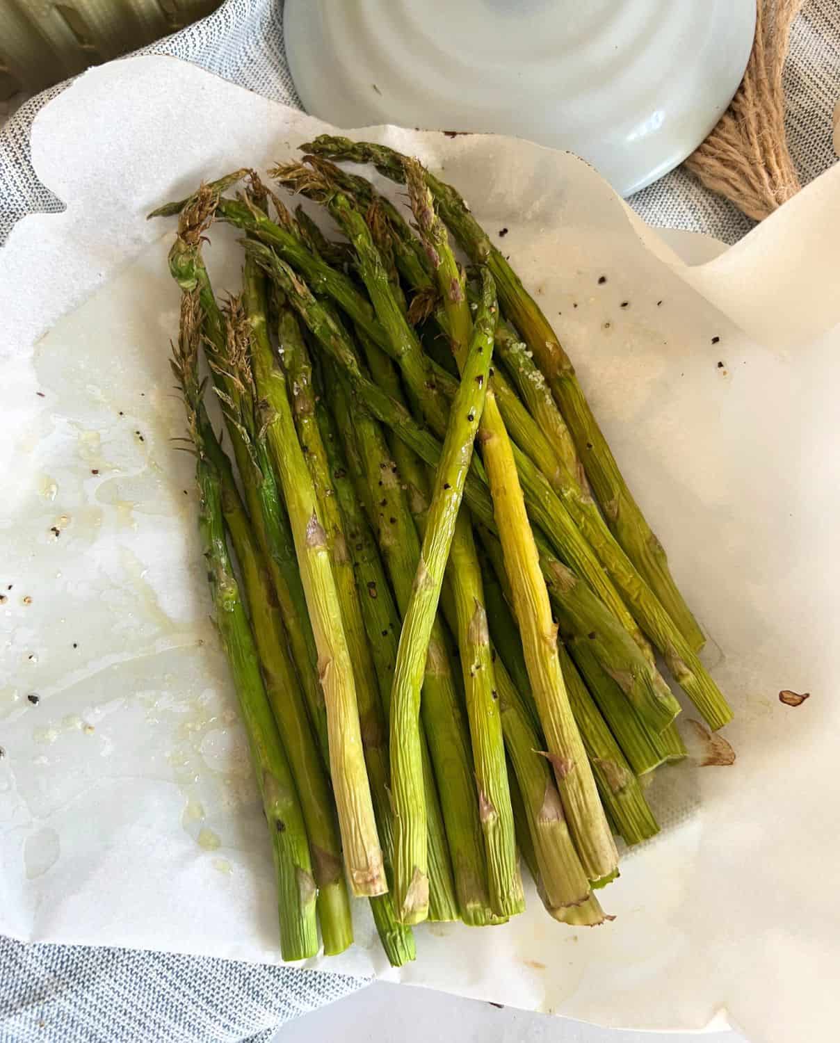Air fryer asparagus on some parchment paper seasoned with salt and pepper. 