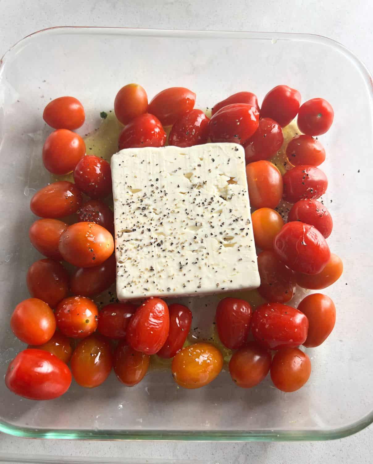 Blocked feta, cherry tomatoes, and olive oil in a casserole dish. 