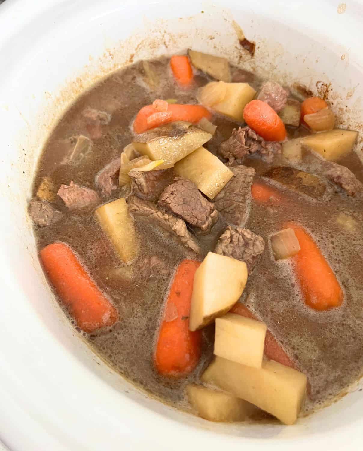 Finished Slow Cooker beef stew in a white crock pot. 