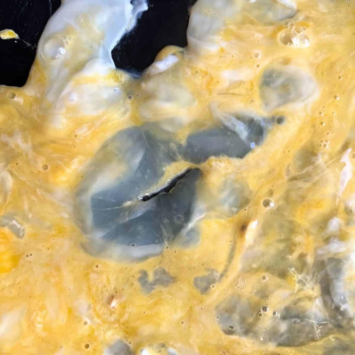 Runny eggs being cooked on a Blackstone griddle. 