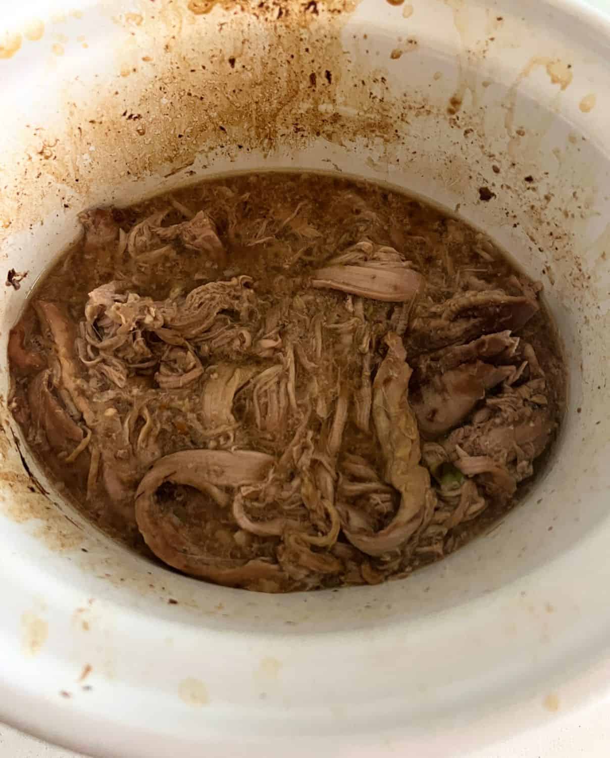 Shredded pork tenderloin in teriyaki sauce in a slow cooker. 