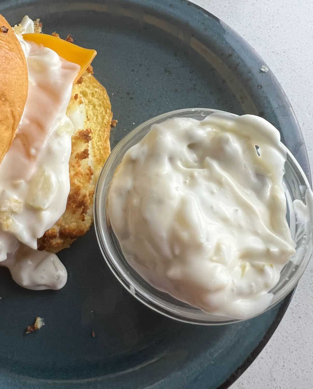 3 ingredient tartar sauce next to a fish sandwich on a plate. 