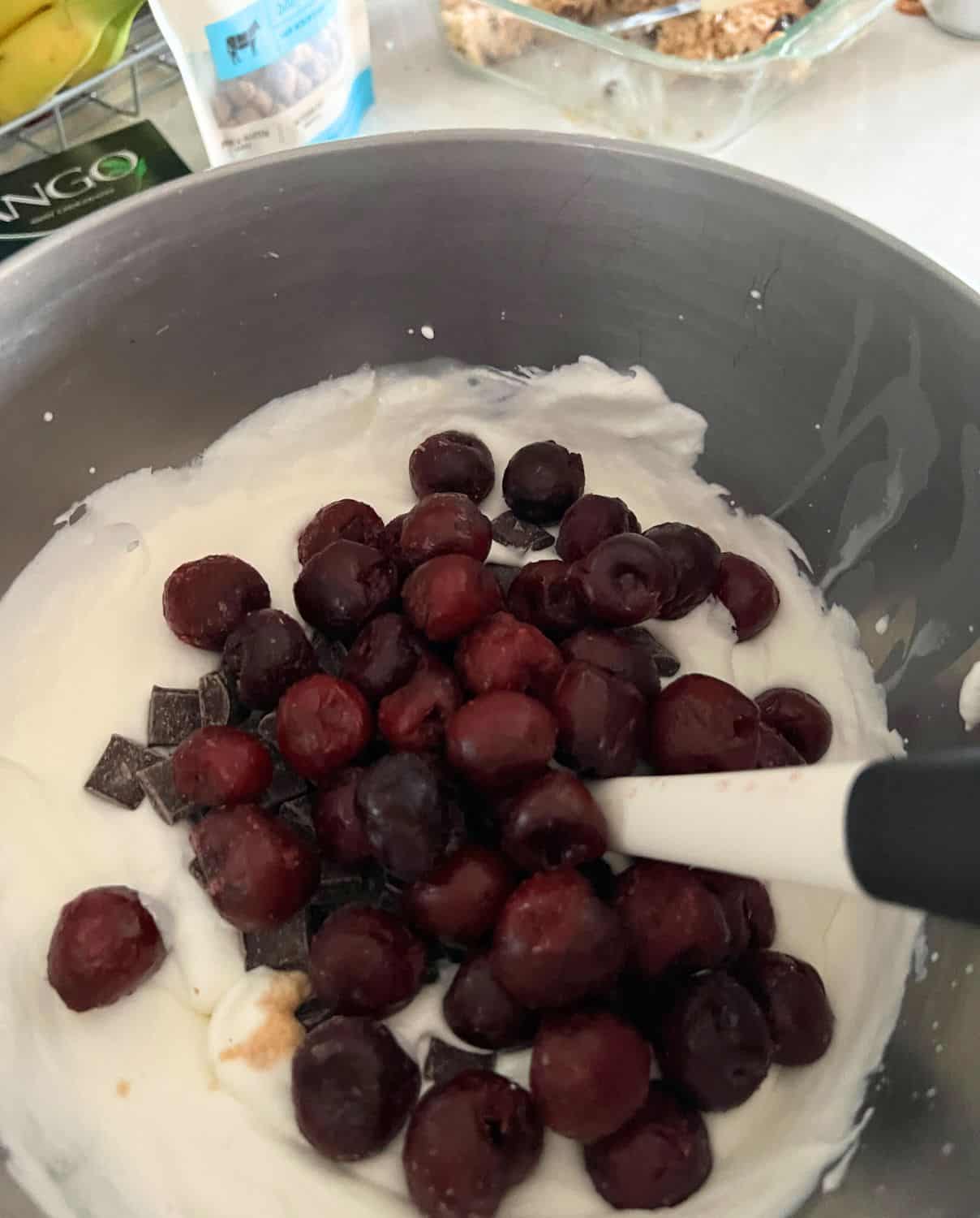 Cherries and chocolate getting mixed into heavy cream mixture. 