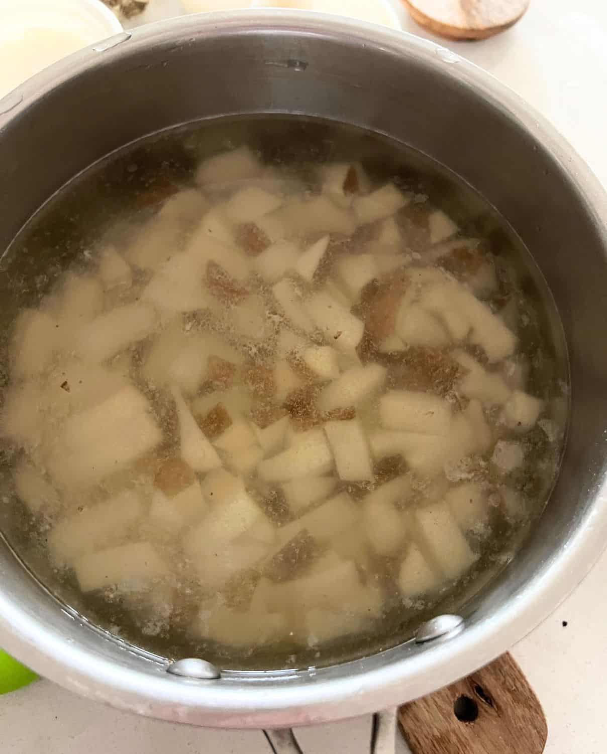 Potatoes and garlic in a sauce pan with water. 