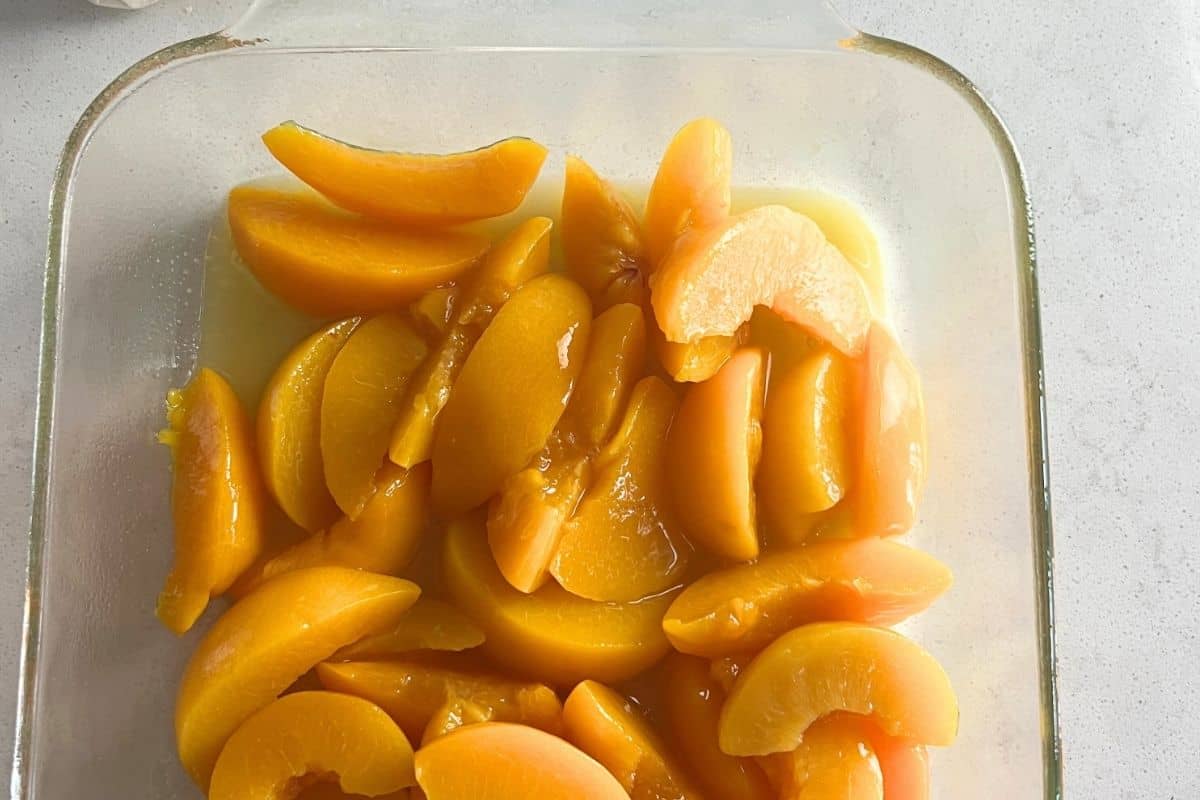 Peaches on the bottom of a baking dish. 