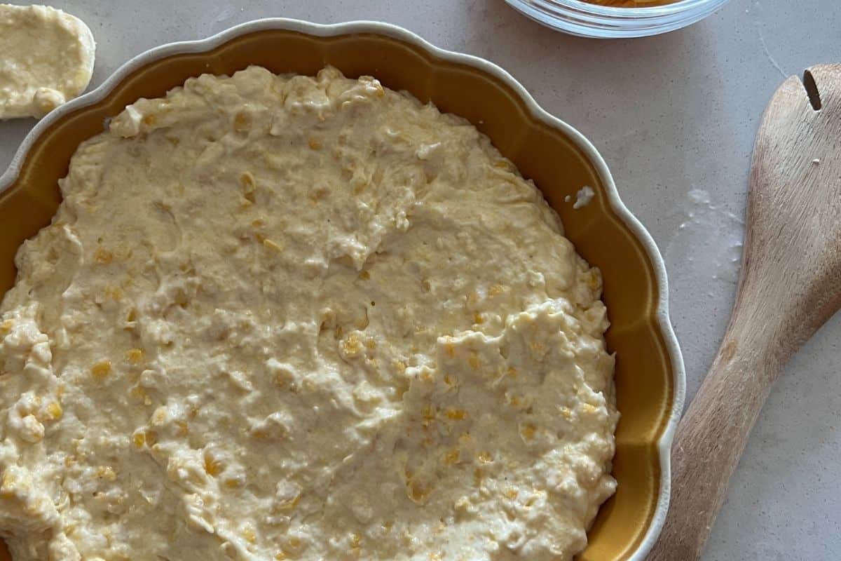 Corn casserole mixture poured into a greased pie dish plate. 