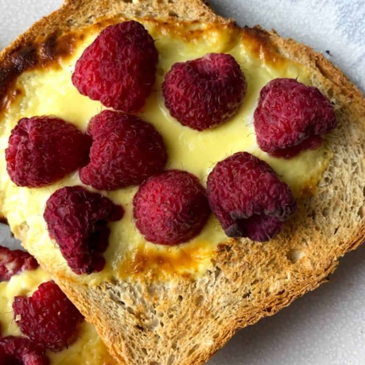 Tiktok custard toast topped with fresh raspberries.