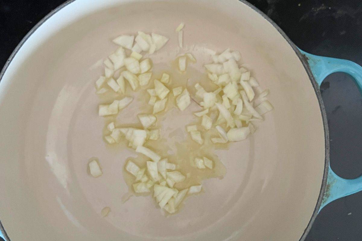 Onions and olive oil cooking in a pan.