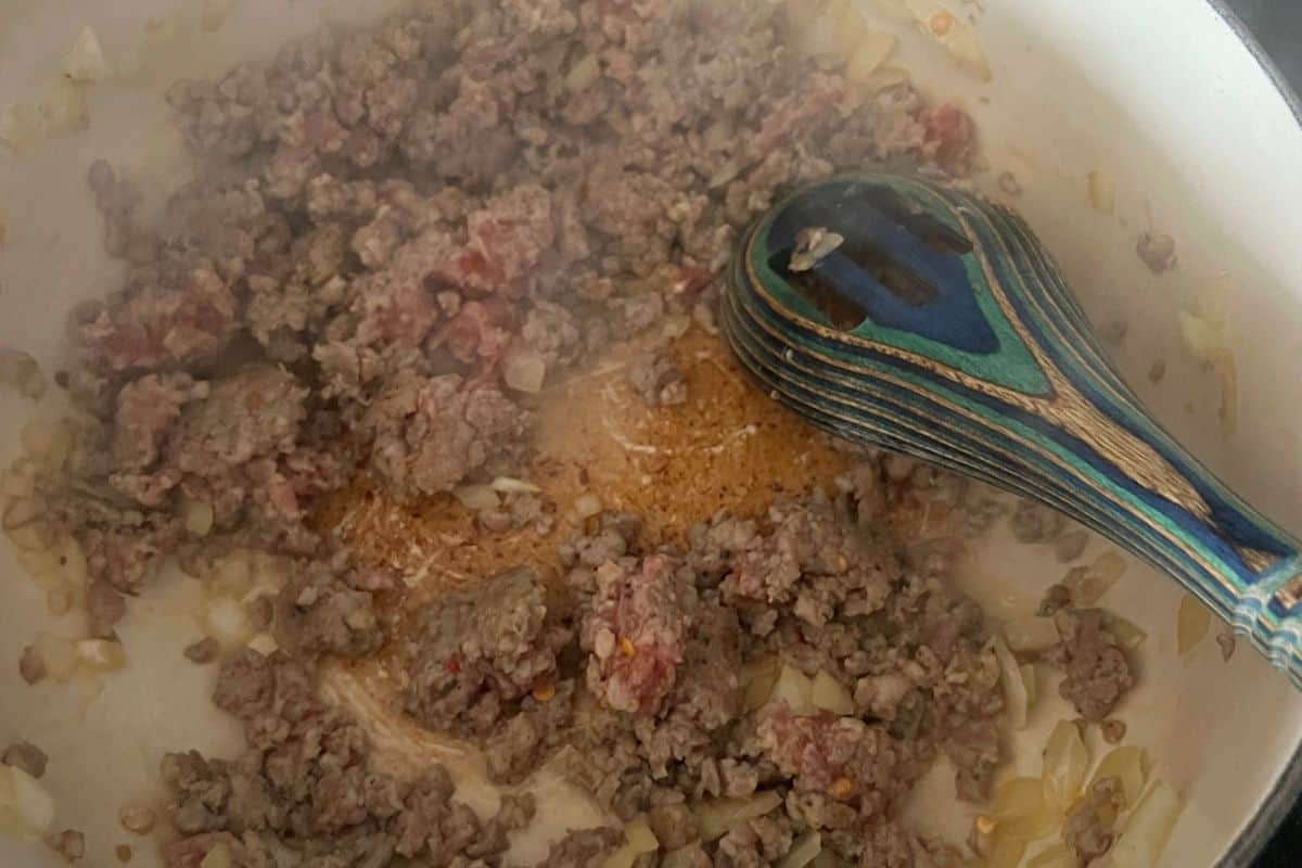 Onions and sausage cooking in a pan. 