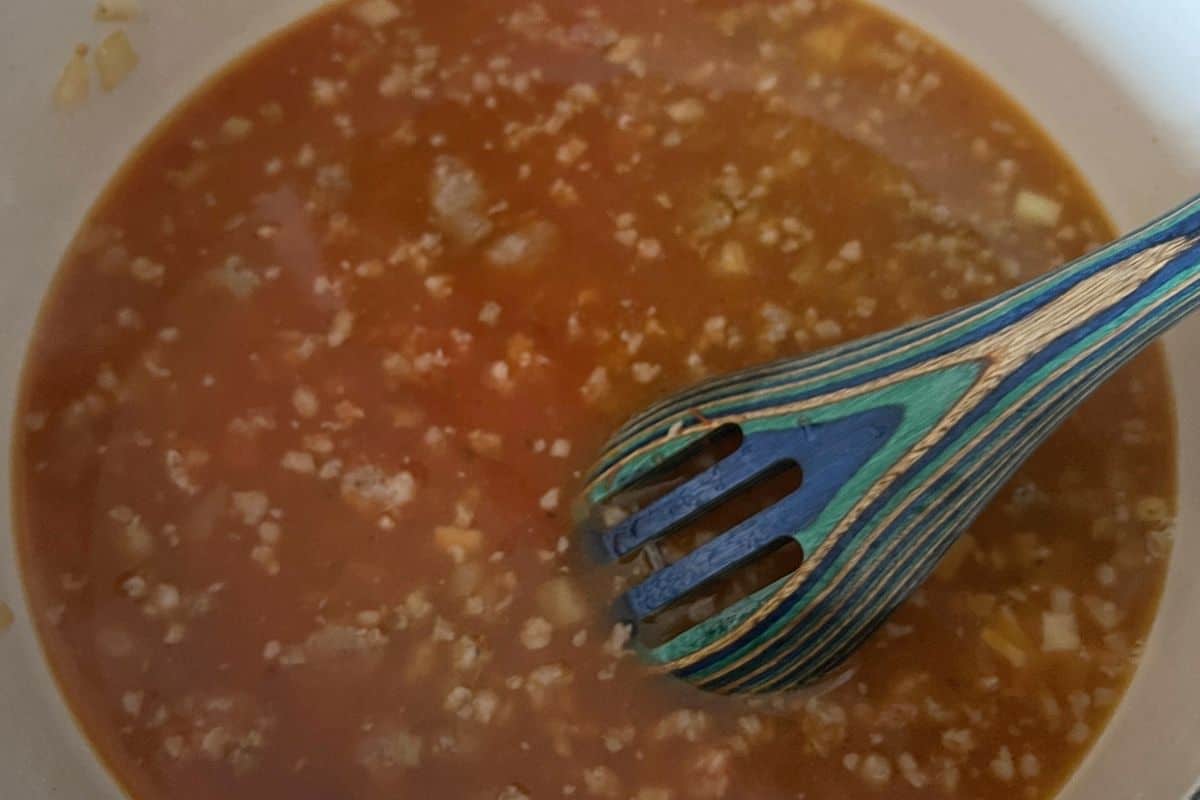 Sausage and tomato sauce boiling in a pan.