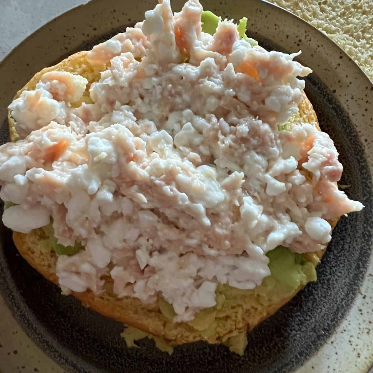 Tuna and cottage cheese on a bun with mashed avocado. 