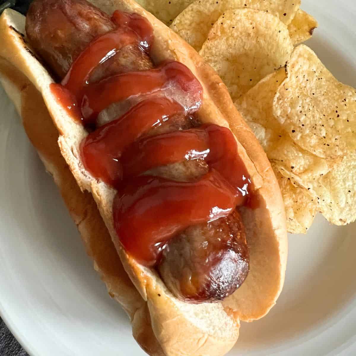 Cooked air fryer brat in a bun topped with ketchup. 