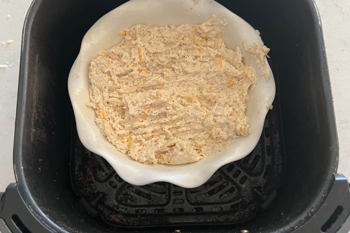 Crab dip in a casserole dish in the air fryer basket. 