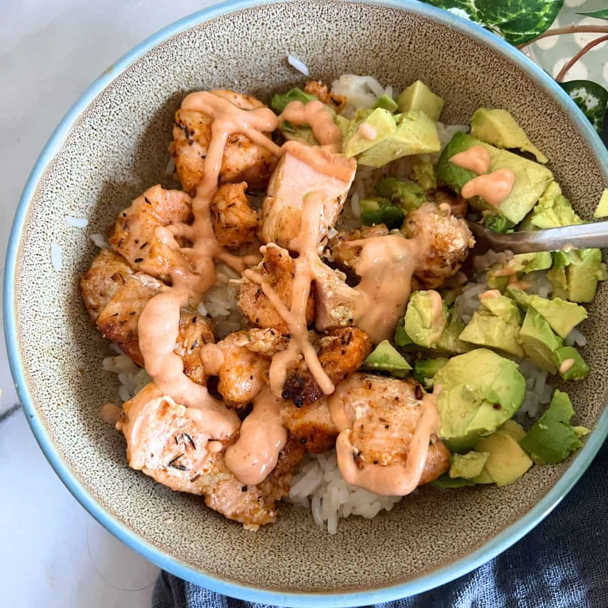 Air Fryer Salmon bites drizzle with spicy mayo on top of rice. 
