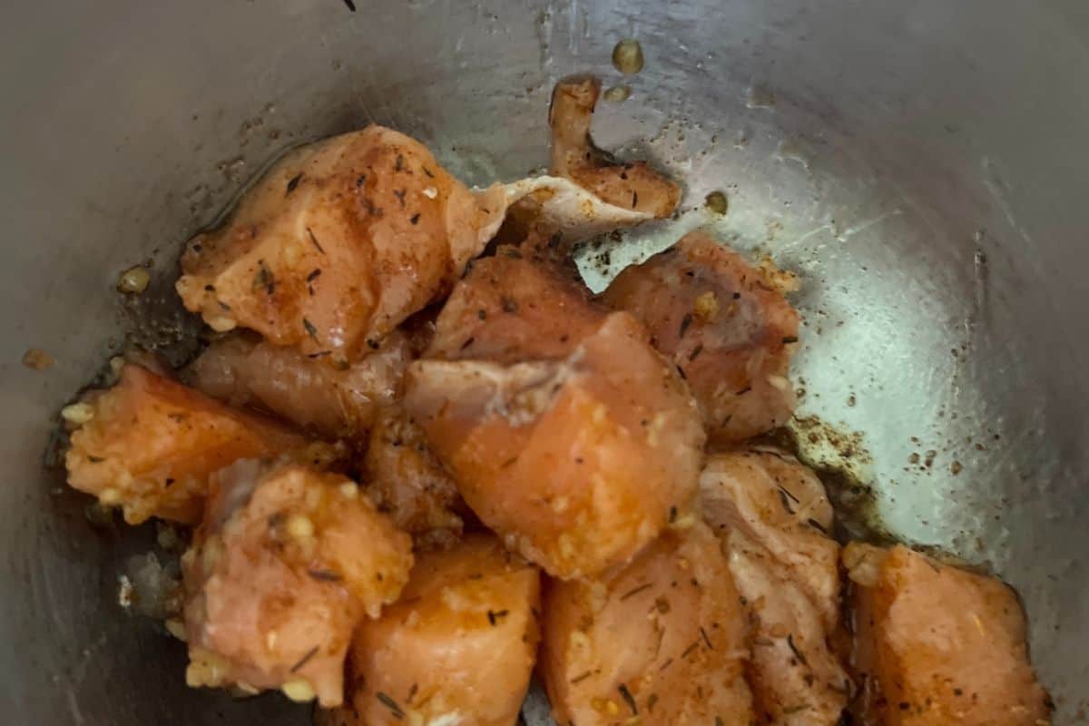 Seasoned air fryer salmon bites in a bowl with olive oil. 