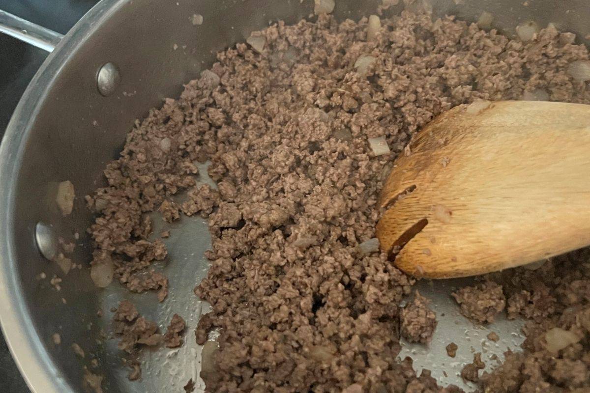 Ground beef and onions cooking in a skillet.